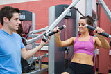 Woman using weights machine with trainer