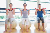 Women lifting weights on exercise balls