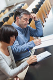 Man and woman taking notes during lecture