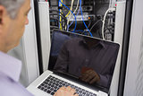 Man sitting in front of a laptop doing server maintenance