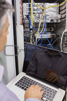 Man sitting with a laptop in front of a server