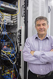 Technician standing beside server with folded arms