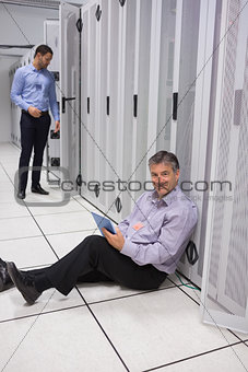 Smiling technician using tablet pc sitting on floor
