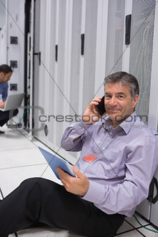 Man phoning while doing maintenance and holding tablet