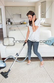 Woman standing holding a vacuum cleaner wearing headphones