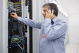 Technician phoning while repairing the server