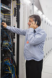 Male technician phoning while repairing a server