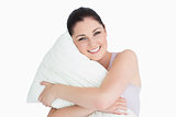 Smiling woman holding a pillow against white background