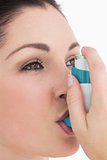 Brunette woman using asthma inhaler