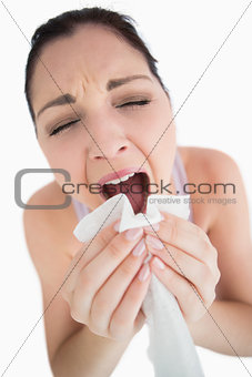 Woman sneezing into a tissue
