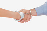 Handcuffed business people shaking hands