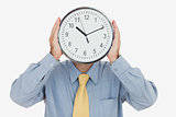 Businessman holding clock in front of face