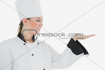 Happy female chef looking at invisible product