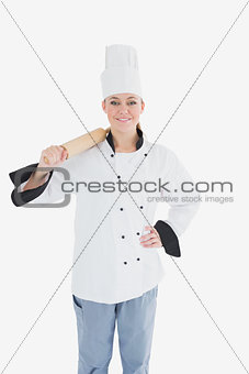 Happy female chef in unifrom holding rolling pin