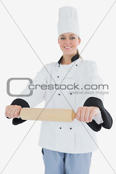 Happy woman in chef clothing holding rolling pin