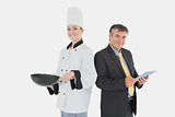 Businessman holding digital tablet and female chef with frying pan