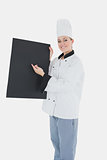 Female chef pointing on black billboard