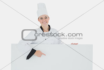 Happy female chef pointing at billboard