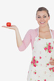 Young woman wearing apron while holding tomato