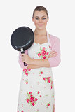 Young woman with arms crossed holding frying pan