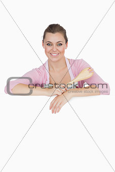 Maid holding spoon as she leans on blank billboard