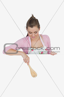 Maid pointing with wooden spoon on billboard