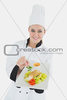 Female chef holding plate of healthy food