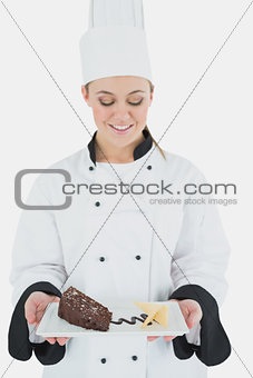 Young female chef holding plate of pastry