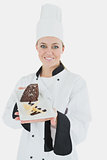 Happy young chef holding plate of pastry