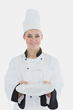 Woman in chef uniform showing an empty plate