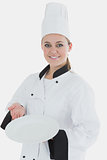 Young woman in chef uniform showing an empty plate