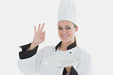 Chef holding an empty plate as she shows ok sign