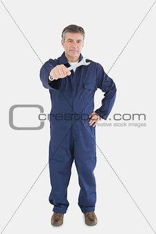 Confident mechanic holding out wrench