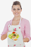 Woman in apron holding dish of healthy meal