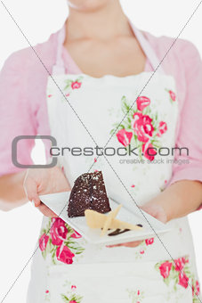 Woman in apron holding plate of tempting pastry