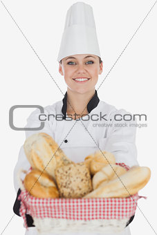 Happy young female chef with bread basket