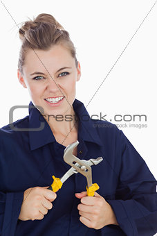 Female mechanic clenching teeth while holding pliers wrench