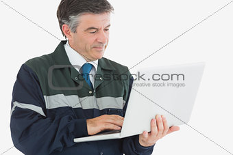Repairman in coveralls using laptop