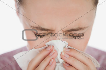 Woman with eyes closed blowing her nose