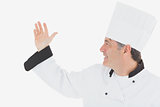 Happy mature chef in uniform gesturing