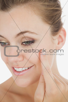 Happy woman applying cream on cheek