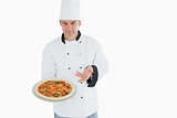 Confident chef displaying pizza