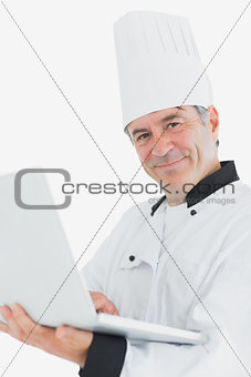Happy male chef using laptop