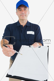 Delivery man holding out clipboard for signature