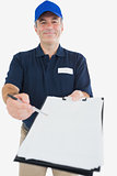 Happy delivery man holding out clipboard for signature