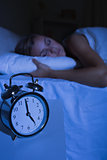 Alarm clock in front of a sleeping woman