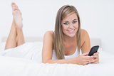 Blonde woman lying on the bed with her phone