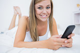 Cute woman lying on the bed with her phone