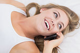 Happy woman phoning lying on the bed