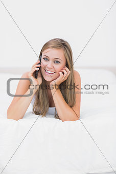 Joyful woman phoning lying on the bed